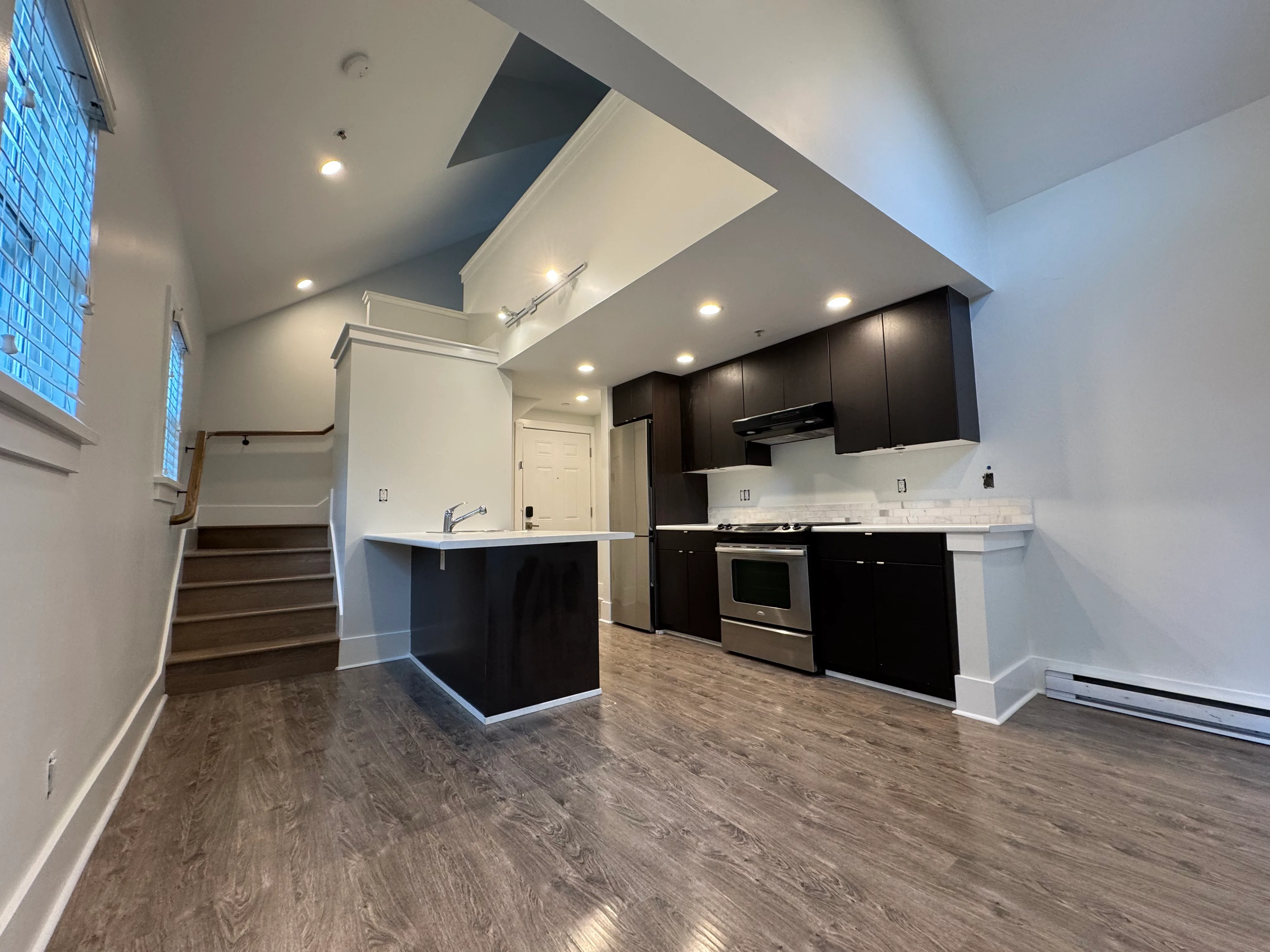 Open kitchen and living space with island and stairs to the loft
