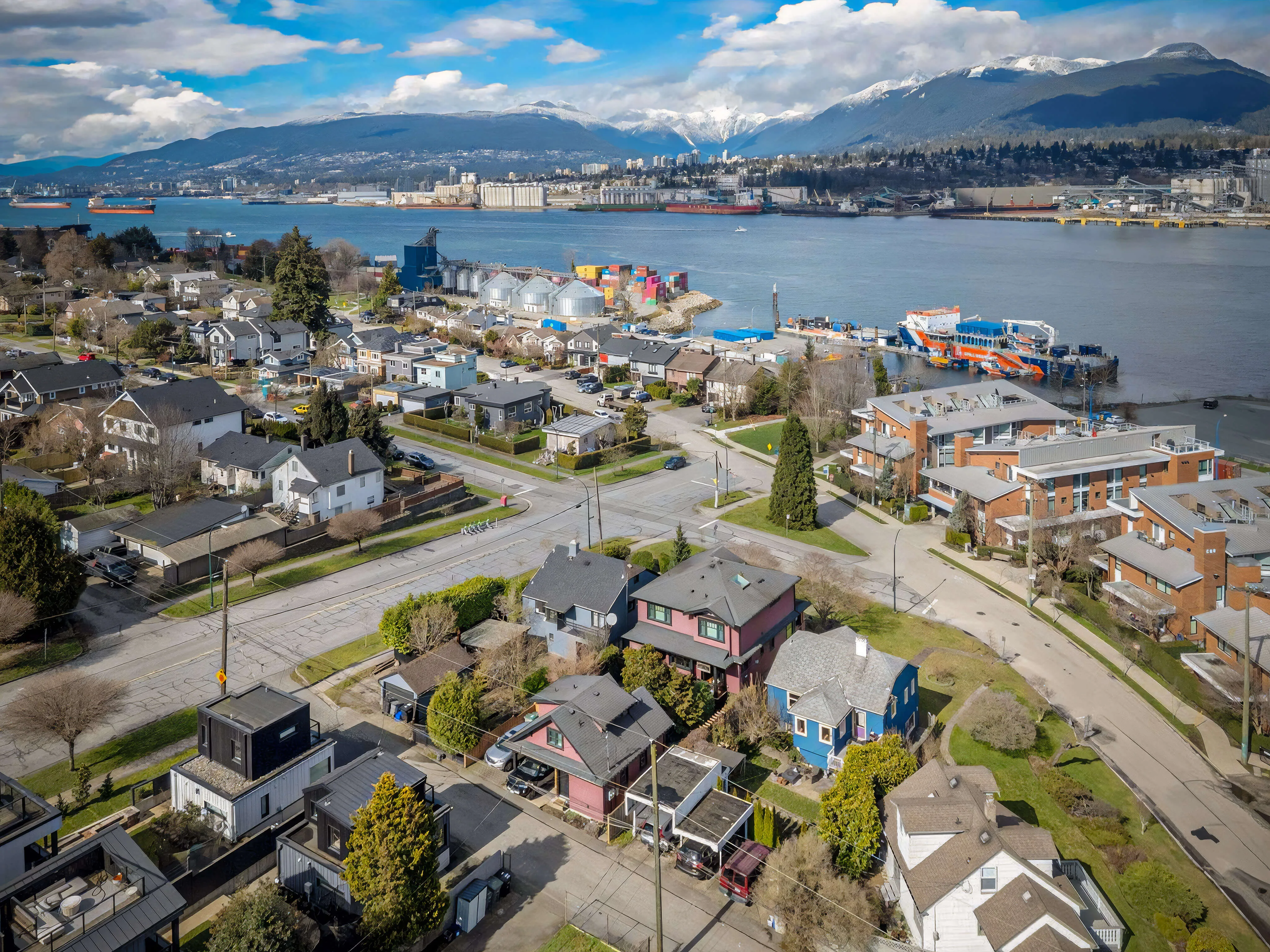 Aerial view over the Hastings-Sunrise rooftops to Burrard Inlet, the working port and the snow-topped North Shore mountains beyond